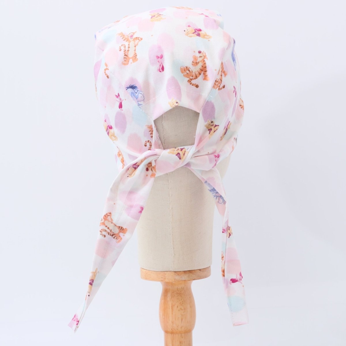 Custom pastel scrub cap by Medicus Caps featuring playful cartoon animals on white and pink background. Back view with adjustable ties, handmade surgical cap made to order.