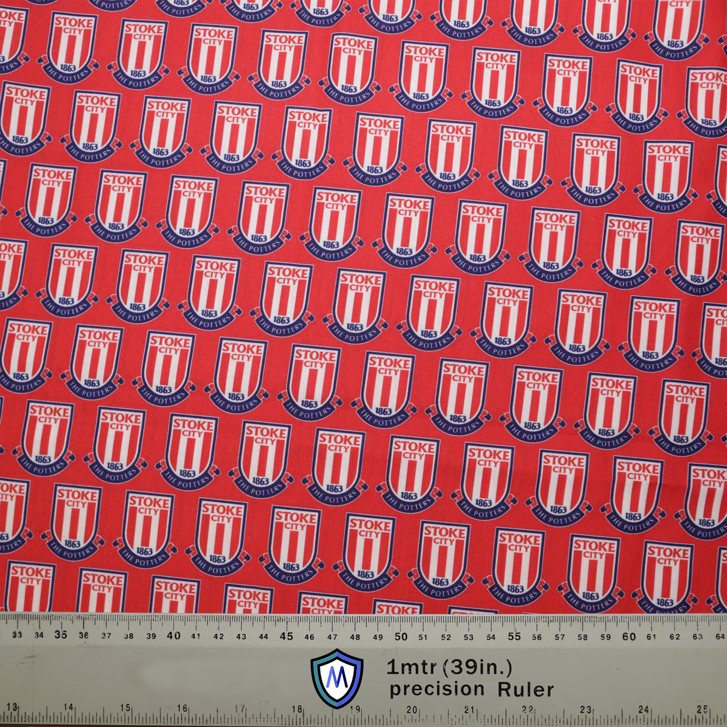 Red fabric with Stoke City FC shield pattern and blue accents for a Medicus Scrub Cap. A 1m (39in) precision ruler at the bottom for scale.