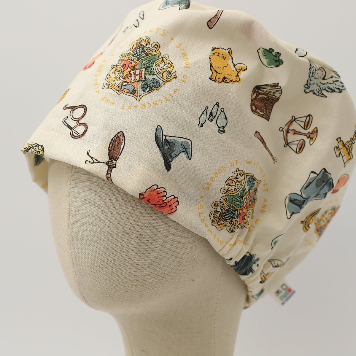 Varita de caldero con el escudo de Harry Potter sobre gorro de quirófano beige