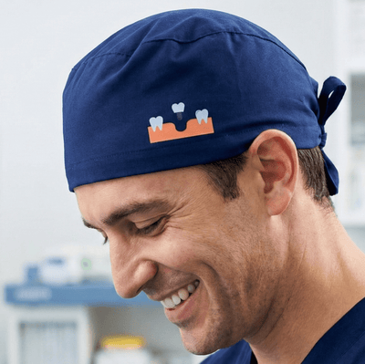 Blue scrub cap with orange crown design showing side profile view of smiling healthcare professional