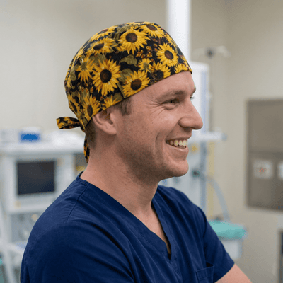 Yellow sunflower pattern scrub cap with navy blue scrubs in medical setting
