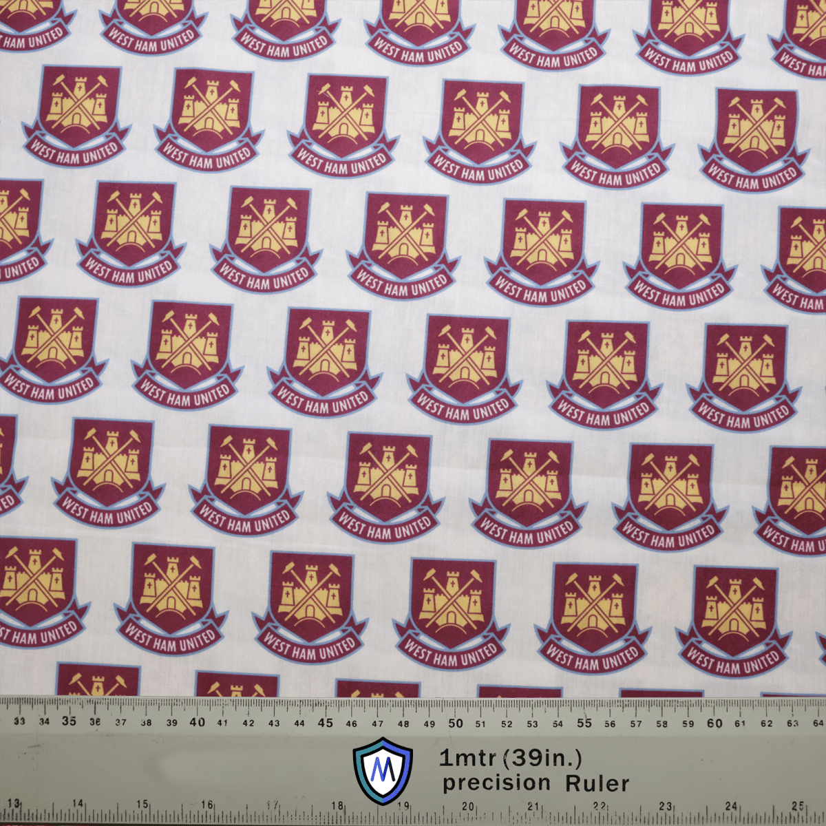 The Medicus Scrub Caps Football Club West Ham United Scrub Cap features a design with repeating gold logos of crossed hammers and a castle on a maroon shield, set against a white background with a precision ruler for scale—perfect for healthcare professionals who are loyal fans.