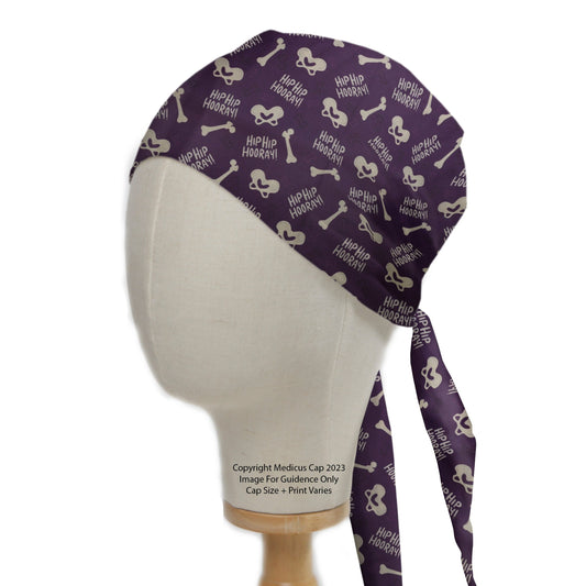 A mannequin displays a purple Medicus Scrub Cap with bones, hearts, and "Hip Hip Hooray!" text, known as the Hip-Hip-Hooray Scrub Cap.