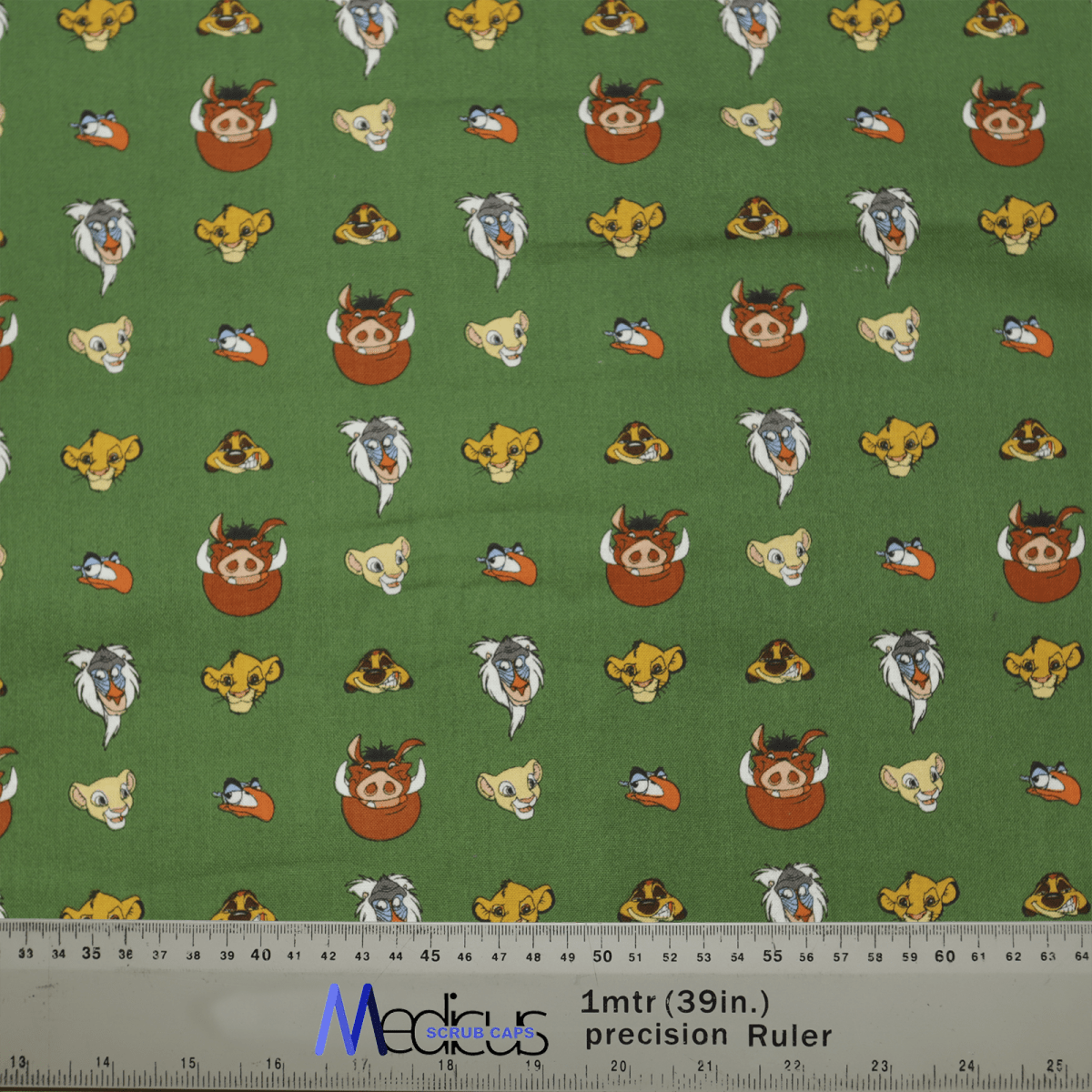 The Disney Lion King #2 Scrub Cap by Medicus features a green fabric with a playful cartoon animal pattern in bright colors like orange, yellow, and white. A ruler at the bottom provides measurements in inches and centimeters. Perfect for adding whimsical Disney magic to your outfit!.