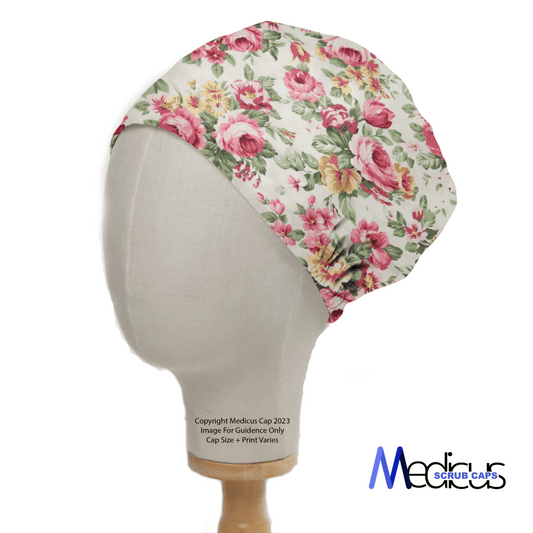 A white mannequin head showcases the Floral Large Roses Vintage Ivory Scrub Cap by Medicus Scrub Caps, featuring large floral roses and verdant leaves against a plain white backdrop. The Medicus Scrub Caps logo appears in the bottom right corner, highlighting its sustainable elegance.