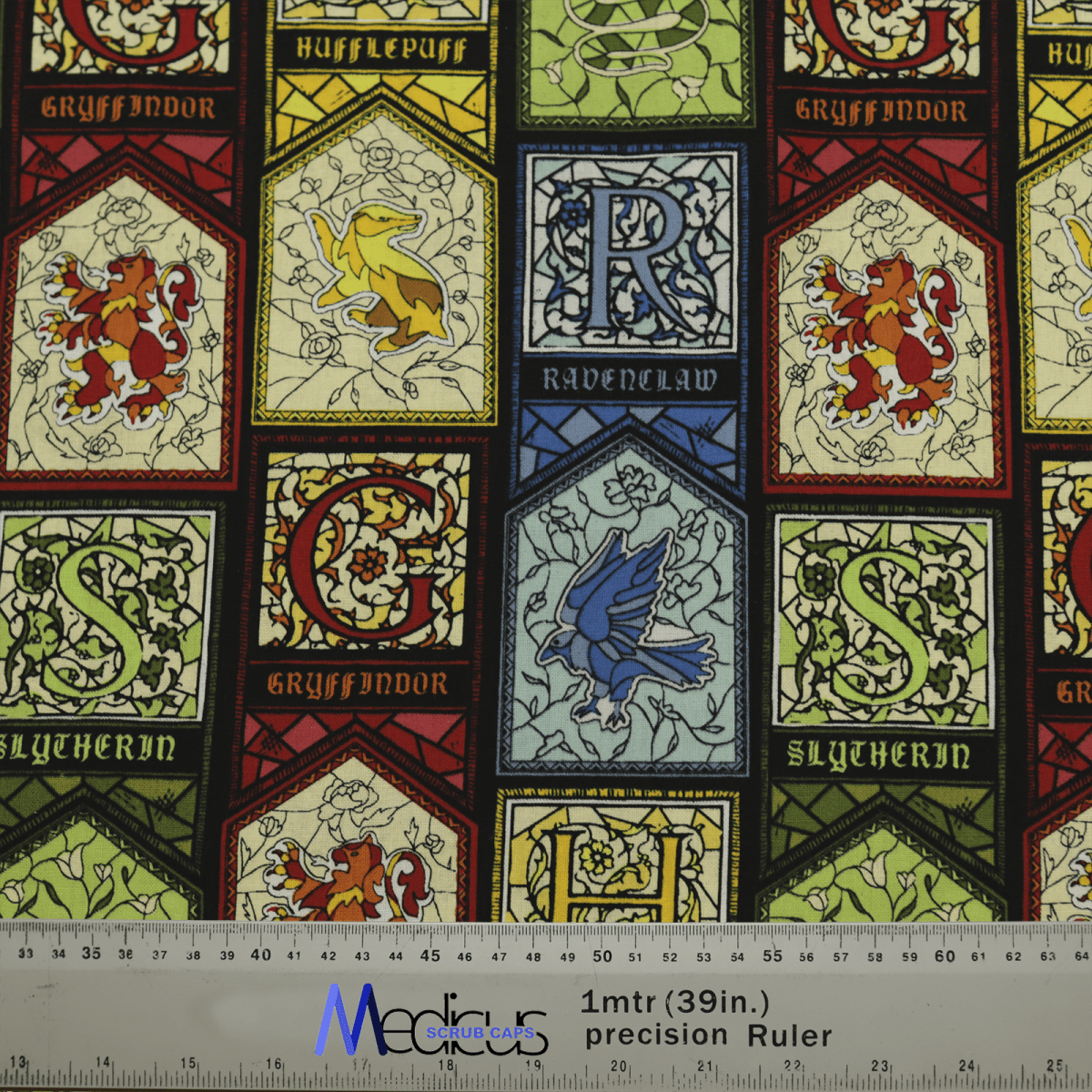 The Medicus Scrub Caps Harry Potter Stain Glass Scrub Cap showcases Gryffindor, Hufflepuff, Ravenclaw, and Slytherin crests in a stained glass style. Its eco-friendly and includes initials with a 1-meter precision ruler scale.