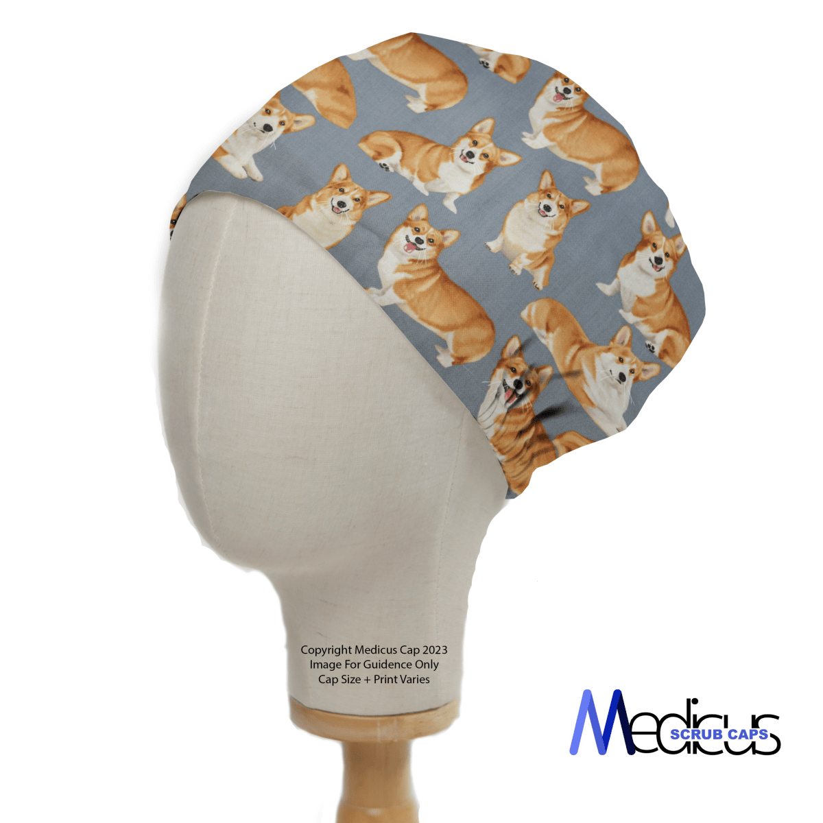 On a gray backdrop, a mannequin head displays the eco-friendly Royal Corgi Dogs Scrub Cap by Medicus Scrub Caps, featuring charming Corgi prints and a visible logo. Note: Image for Guidance Only, Cap Size + Print Varies.