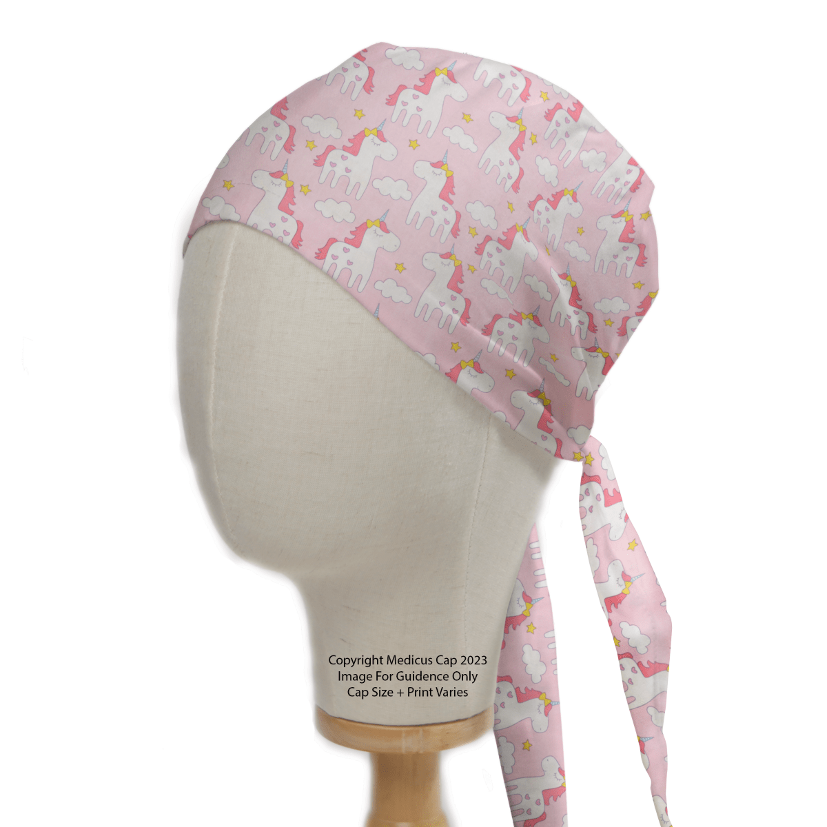 The Medicus Scrub Caps Unicorn Cartoon Pink Scrub Cap is displayed on a mannequin head, featuring colorful unicorns among clouds and stars on a light pink background with long ties—an enchanting addition to your sustainable scrub caps collection.