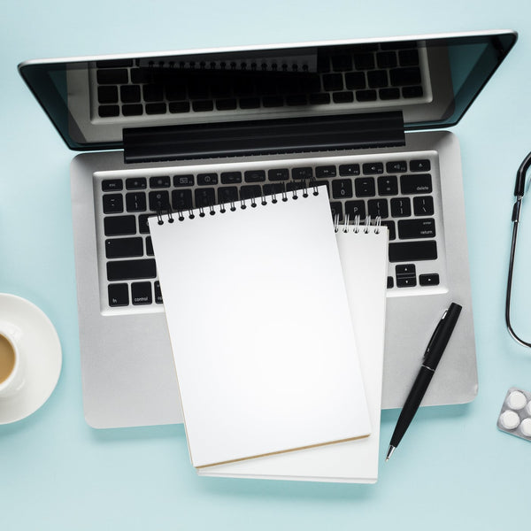 Medical research desk with laptop, journal, stethoscope and coffee