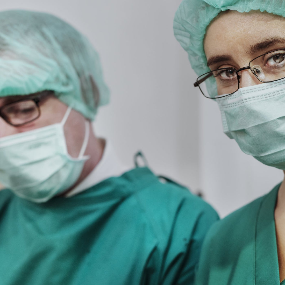 Two surgeons wearing green scrub caps