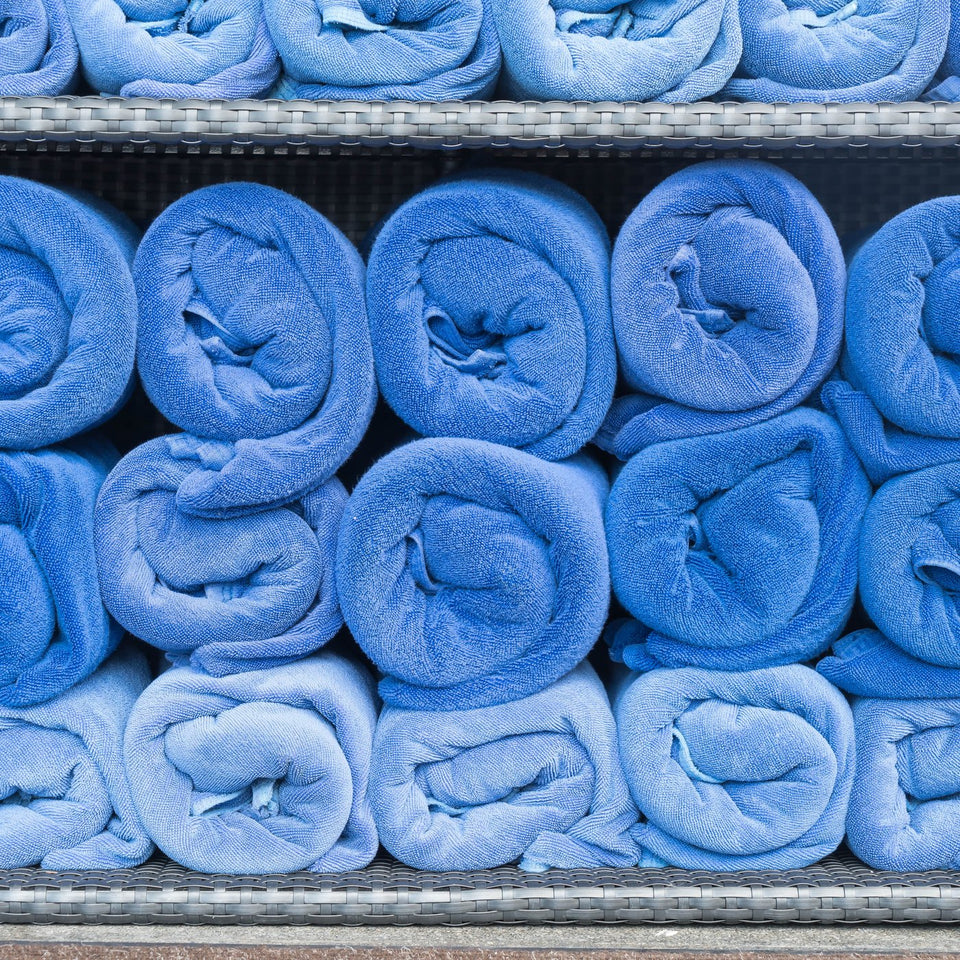 Rolled blue medical scrubs stacked on shelves