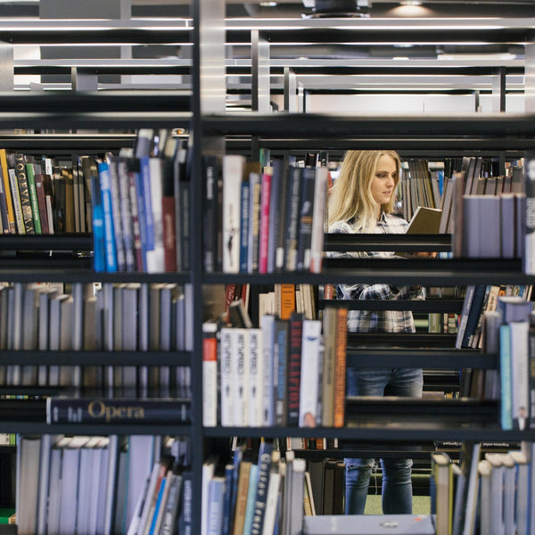 Person researching among library bookshelves