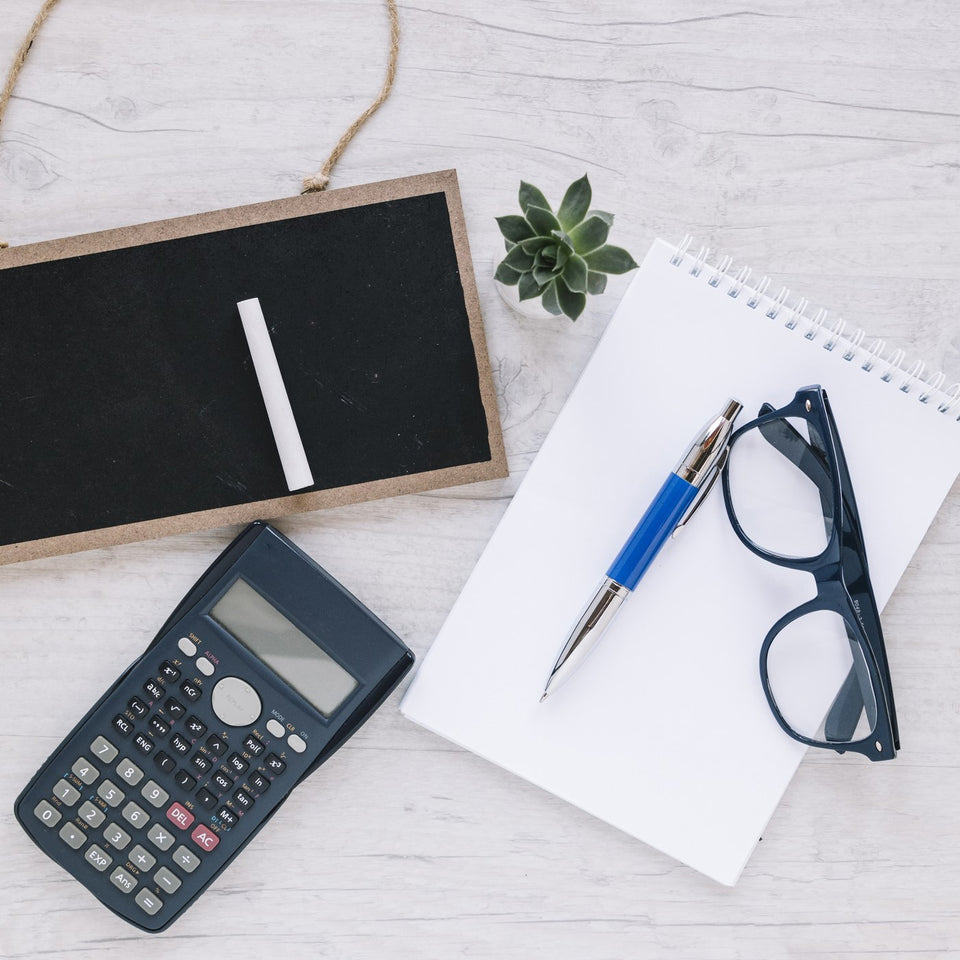 Calculator, notepad and glasses on a desk