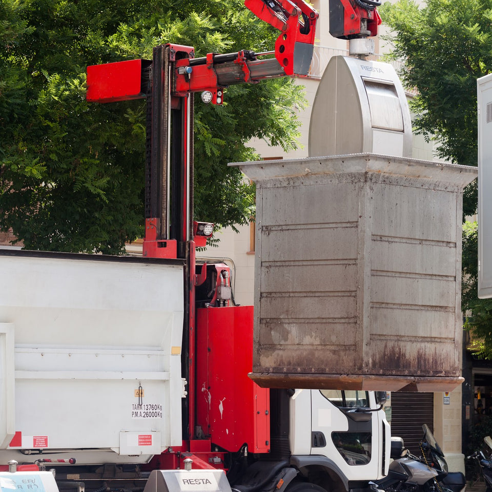 Garbage truck lifting a large waste container on a city street
