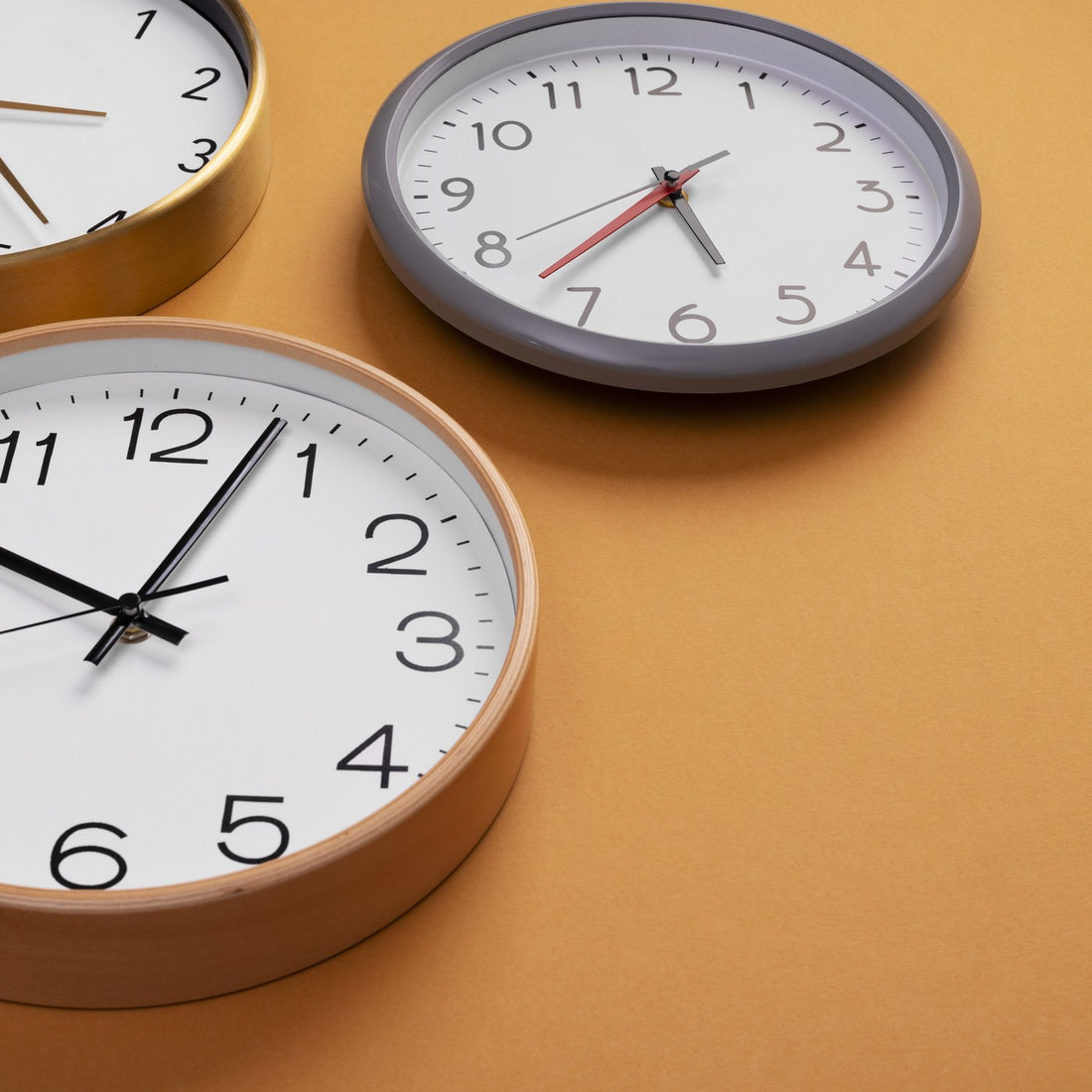 Several round wall clocks arranged on an orange background