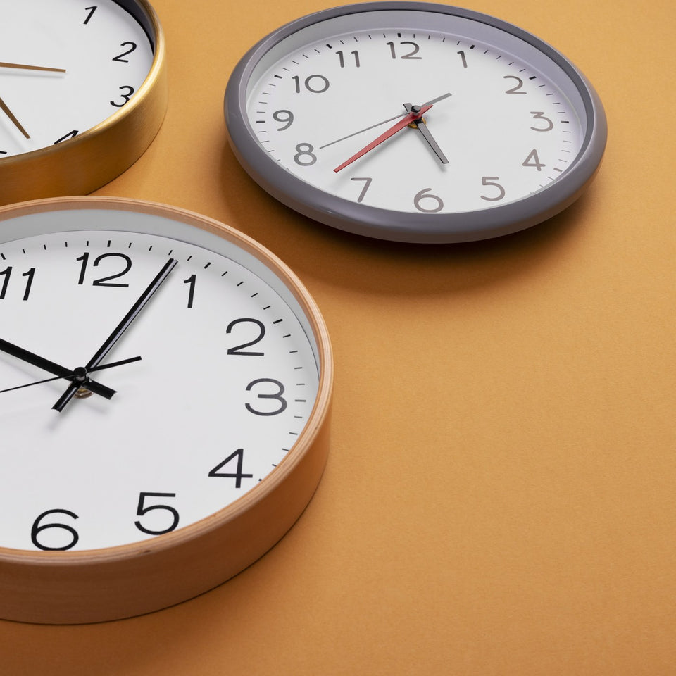 Several round wall clocks arranged on an orange background
