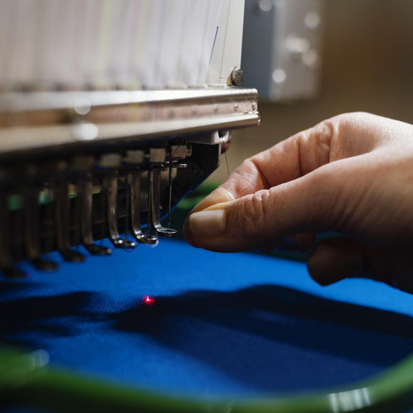 Close-up of an embroidery machine stitching blue fabric