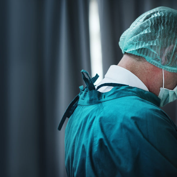Back view of a surgeon wearing a green surgical cap in a hospital