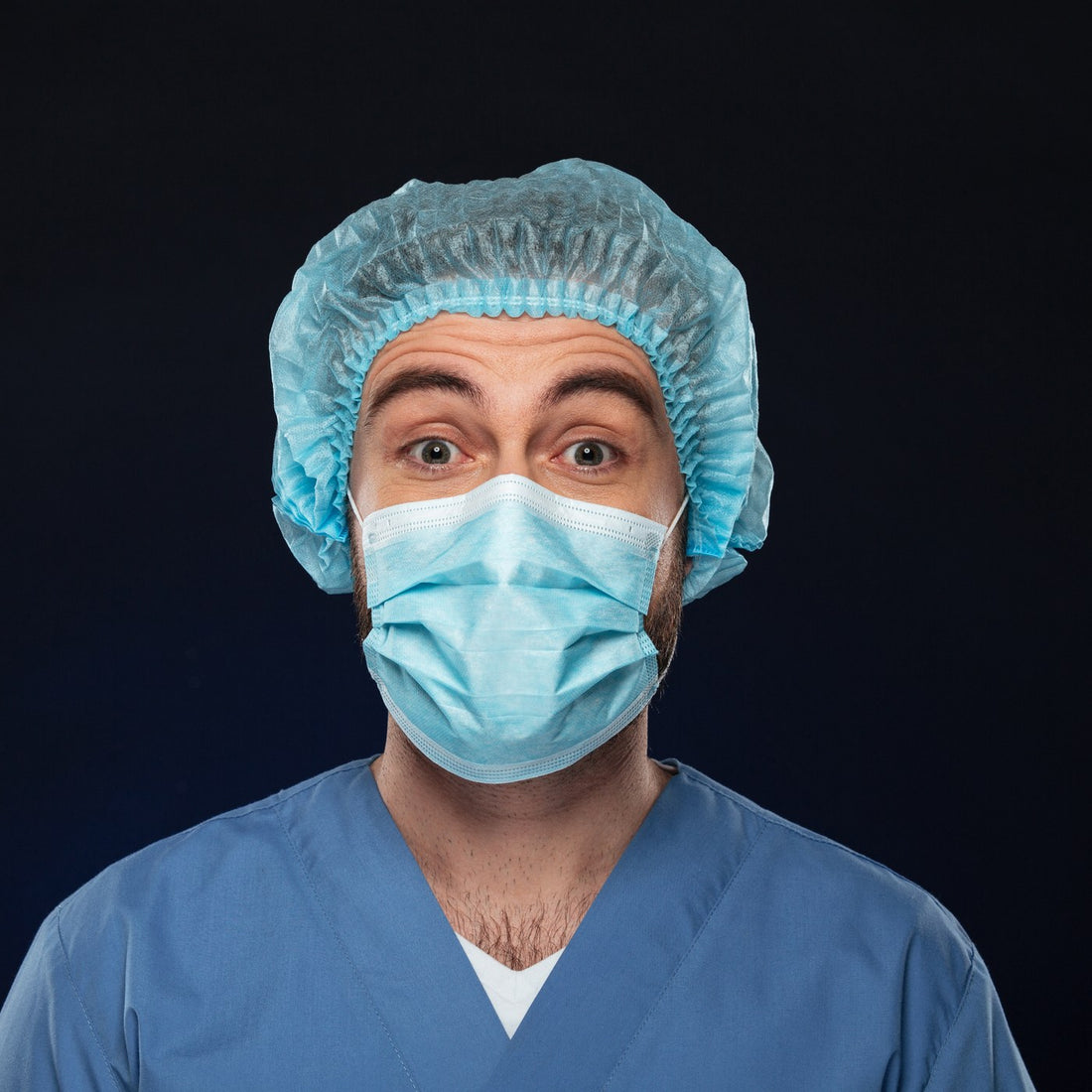 Close-up of a surgeon wearing a blue scrub cap and face mask