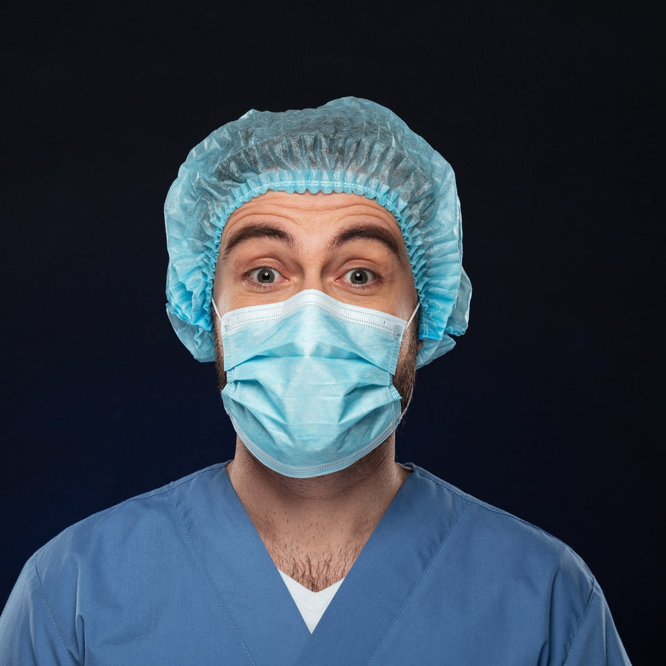Close-up of a surgeon wearing a blue scrub cap and face mask