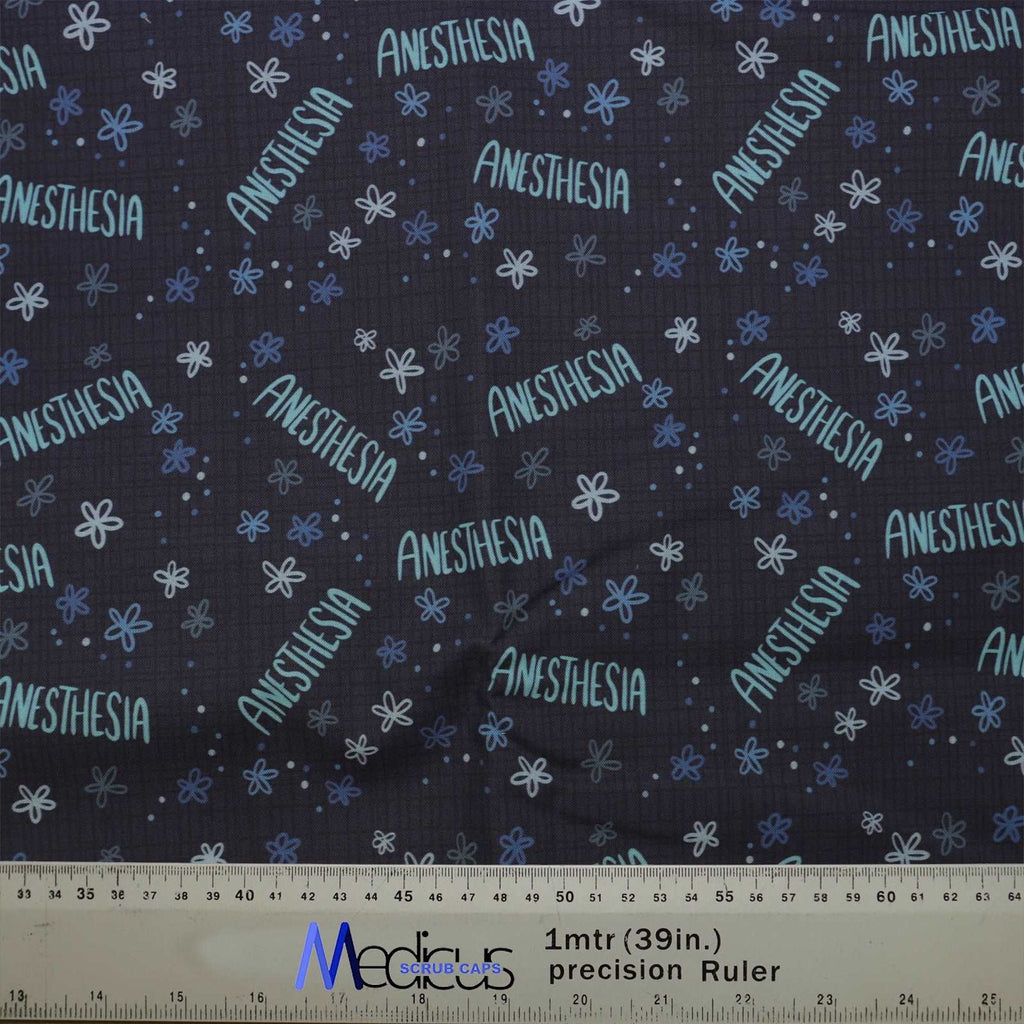 The Anaesthetist Anaesthesia Scrub Cap from Medicus Scrub Caps features "ANESTHESIA" in blue tones with small flowers, combining style and function. Ruler included for scale.