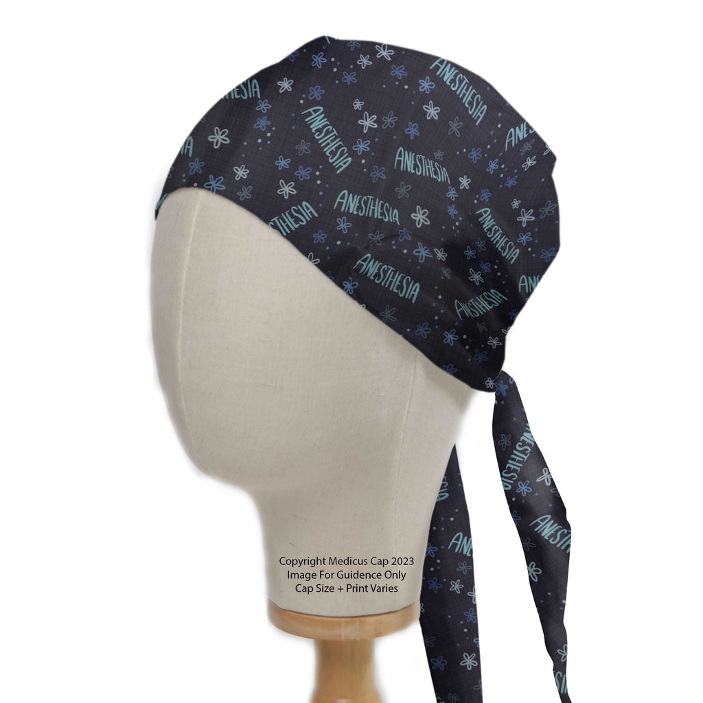 The mannequin displays a black Medicus Scrub Cap with "ANESTHESIA" and blue snowflake patterns, offering stylish, adjustable full-head coverage for anaesthetists.