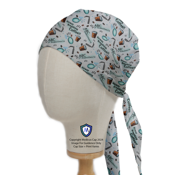 On a mannequin head, the Anaesthetist ABCs Scrub Cap by Medicus Scrub Caps features coffee cups, stethoscopes, and vials, emphasizing anesthesia and teamwork with a neat tie-back.