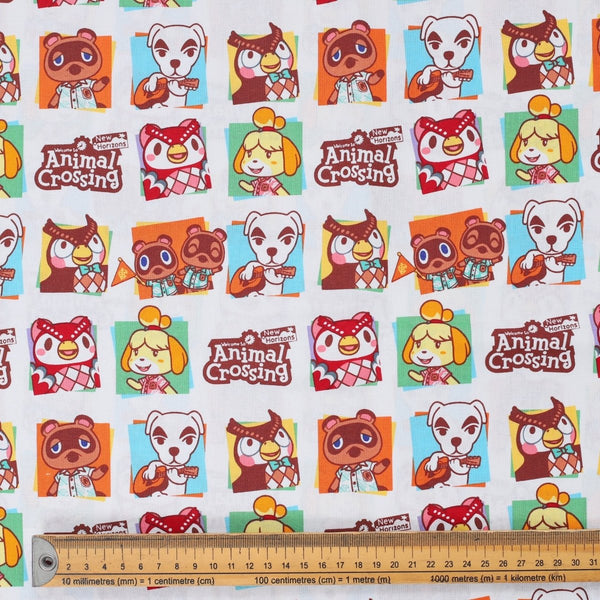 Close-up of Animal Crossing cartoon fabric with characters in square frames and ruler for scale.