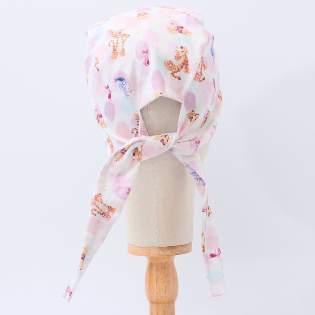 Custom pastel scrub cap by Medicus Caps featuring playful cartoon animals on white and pink background. Back view with adjustable ties, handmade surgical cap made to order.