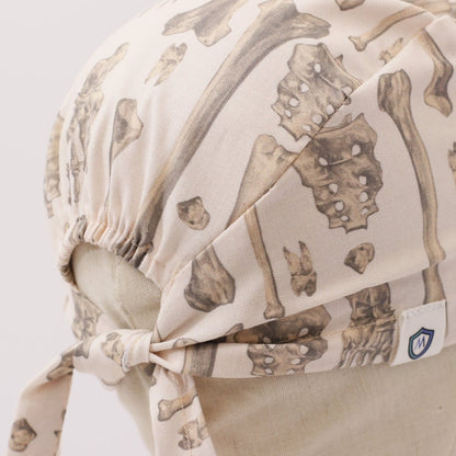 Beige custom scrub cap with bone pattern design tied at the back, handmade by Medicus Caps