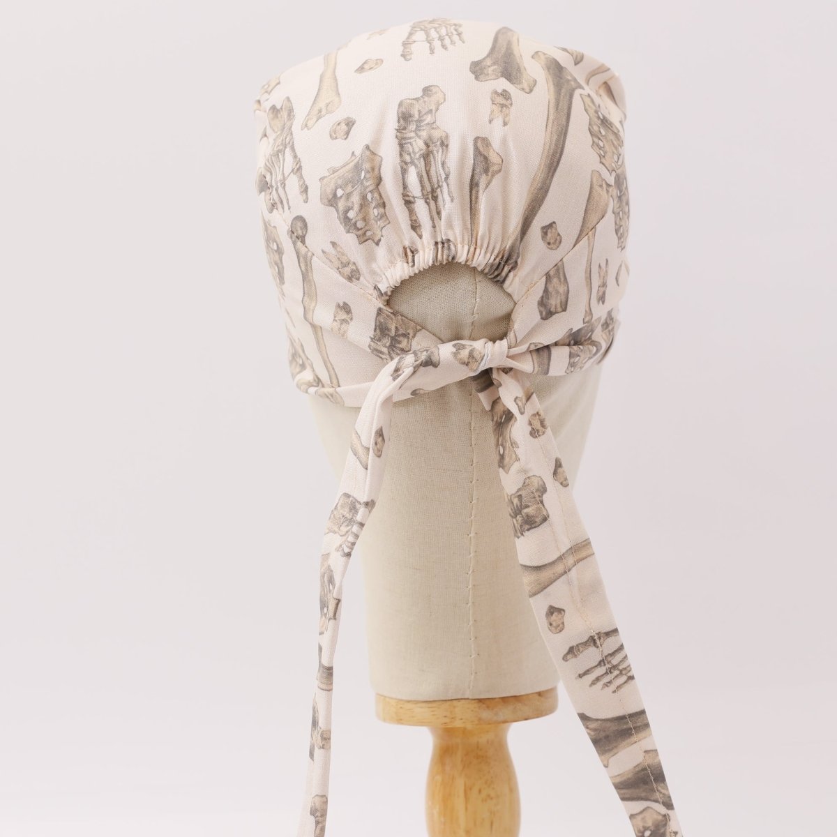 Back view of beige custom scrub cap with bone pattern, handmade by Medicus Caps