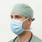 Person wearing a light green surgical cap and blue face mask on a white background