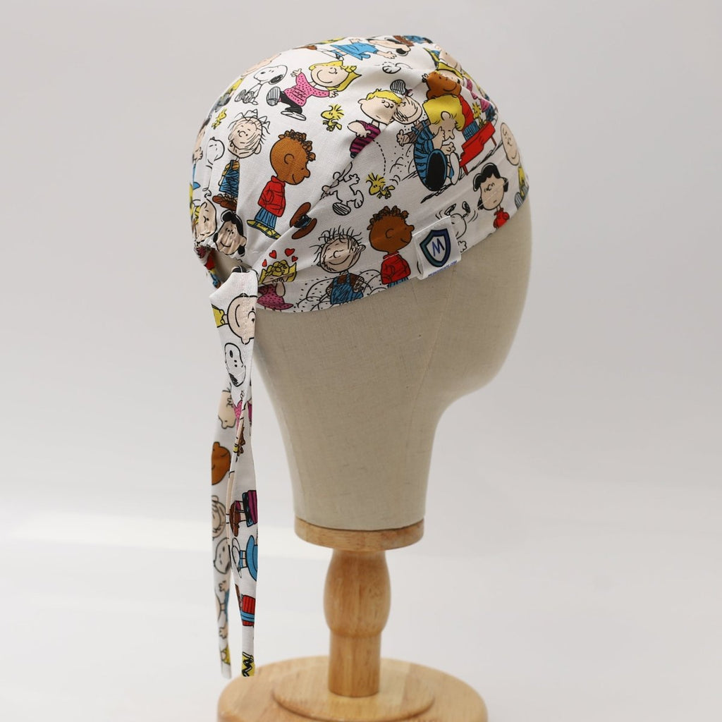 Custom scrub cap by Medicus Caps featuring colourful cartoon character print on white fabric. Side view with long tie strap; handmade surgical cap made to order.