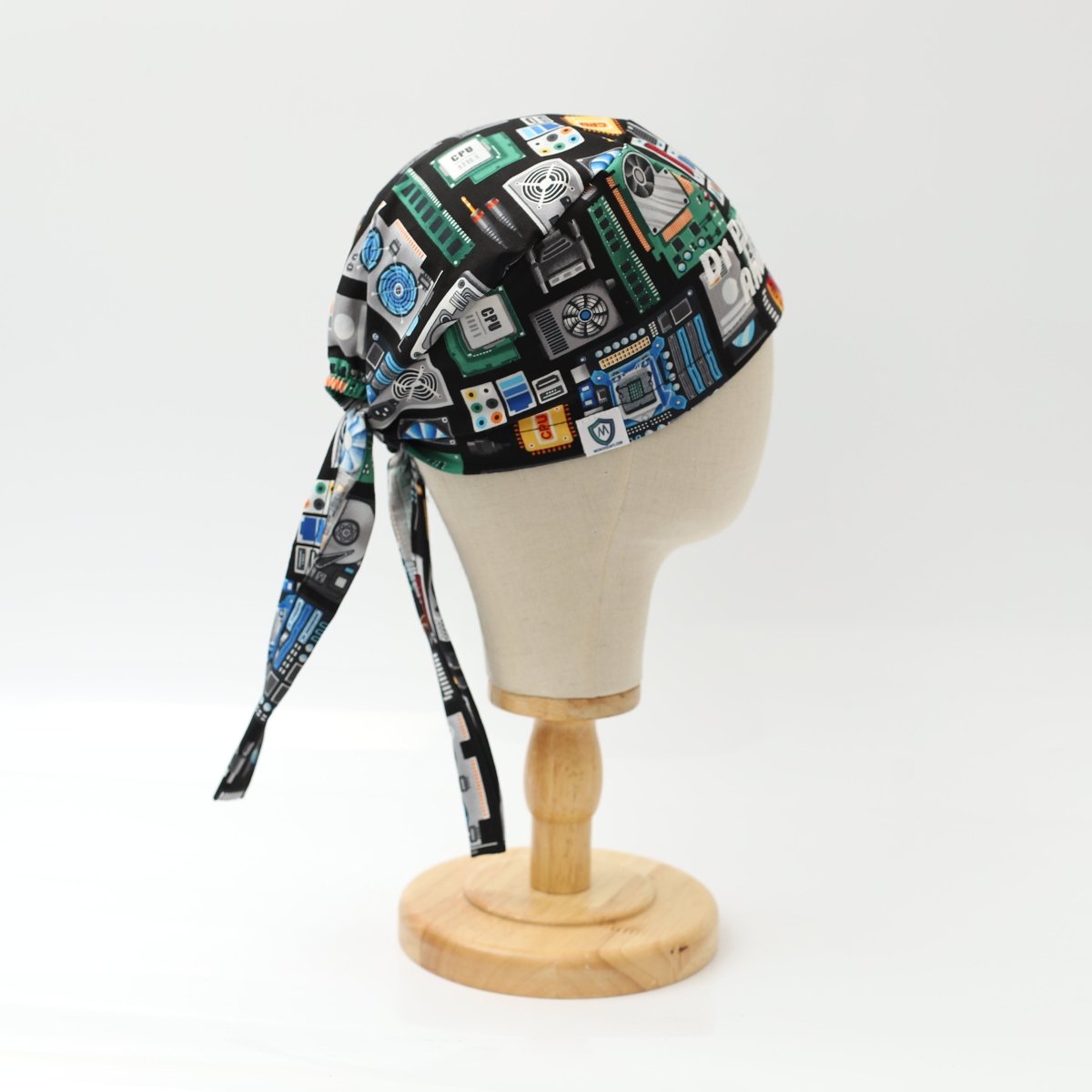 Medicus Scrub Cap with a circuit board and computer-themed design, displayed on a mannequin head. Black background with colorful tech-inspired details.