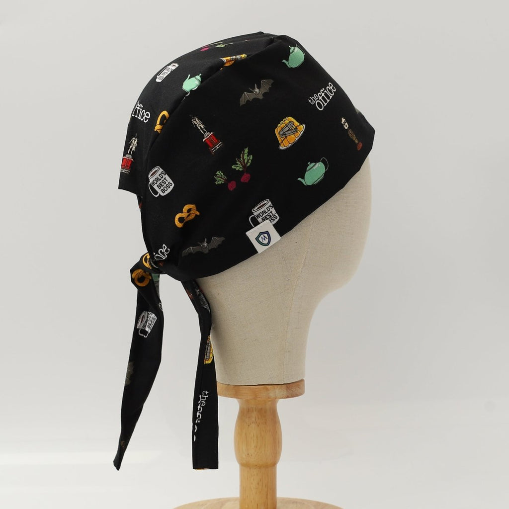 Side view of black custom scrub cap featuring coffee and tea-themed illustrations including French press, teapots, grinders and cups. Handmade coffee barista scrub cap by Medicus Caps with tie-back design ideal for medical professionals who love coffee.