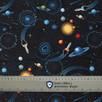 Close-up of space-themed scrub cap fabric showing colorful planets, rockets, and spaceships on black background