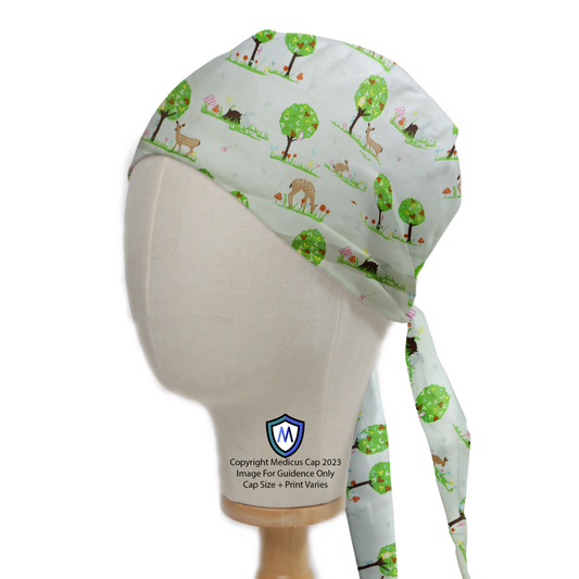 A mannequin head wears the Deers In Park Trees Scrub Cap by Medicus Scrub Caps, featuring a serene nature-themed design with deer, trees, and greenery.