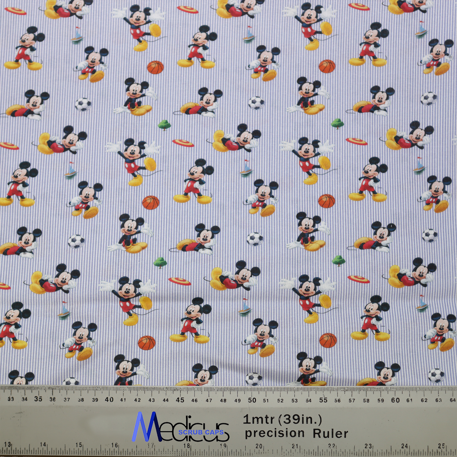 The Disney Mickey Football Frisbee Scrub Cap by Medicus Scrub Caps features Mickey playing sports on striped fabric, with a ruler for precise measurements—perfect for crafting.