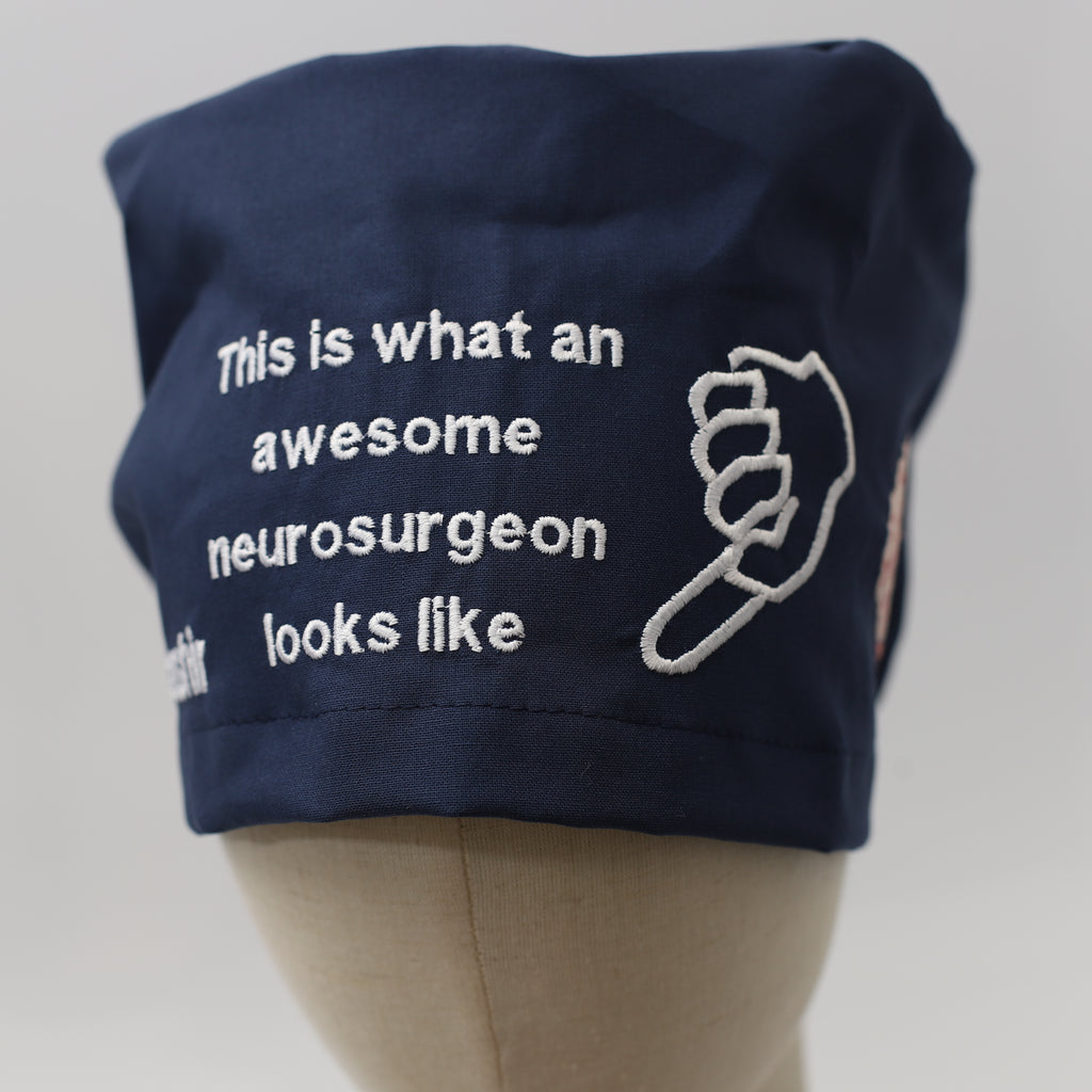 Navy blue Medicus Scrub Cap with white embroidery reading "This is what an awesome neurosurgeon looks like" alongside a pointing hand design.