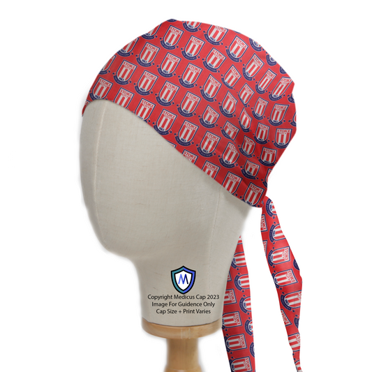 A mannequin head wears a red Medicus Scrub Cap featuring Football Club Stoke City FC logos, with tie strings elegantly draped down the side.