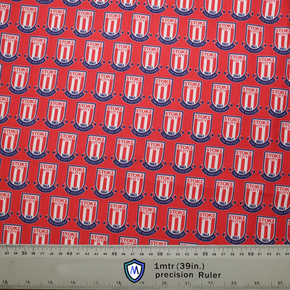 Red fabric with Stoke City FC shield pattern and blue accents for a Medicus Scrub Cap. A 1m (39in) precision ruler at the bottom for scale.