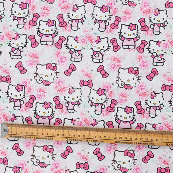 Close-up of Hello Kitty in pink rose garden print with bows and roses, fabric swatch with ruler for scale.