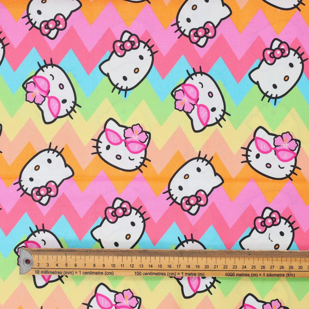 Close-up of Hello Kitty on pastel rainbow zigzag fabric with chevron pattern and ruler for scale.