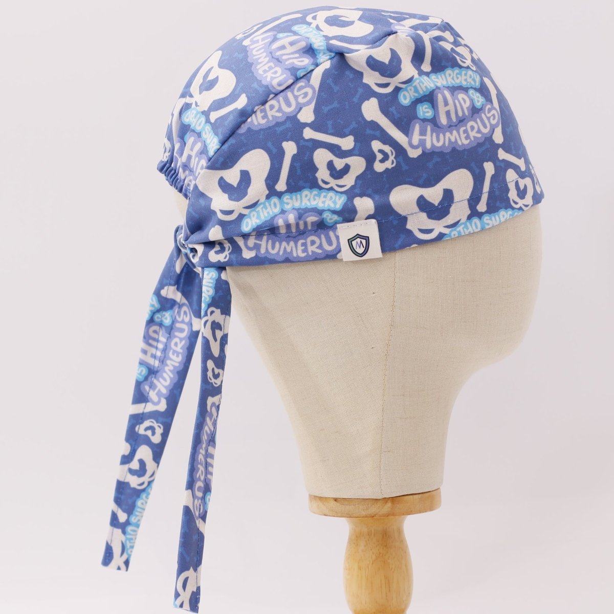 Side view of blue custom scrub cap with hip and humerus bone pattern, handmade by Medicus Caps