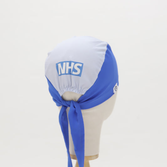 A mannequin head displays the Mullet Version: Make Your Own Custom Printed Scrub Cap by Medicus Scrub Caps, featuring a blue and white NHS design, tied neatly.