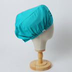 Turquoise reusable scrub cap with button details shown on white mannequin head, side view