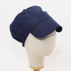 Navy blue scrub cap with peaked visor shown in side profile view on mannequin head