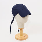 Navy blue scrub cap with tie closure shown in side profile on wooden mannequin head