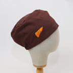 Brown scrub cap with orange smiley pancreas design shown from side angle on mannequin head