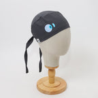 Black scrub cap with blue eye design shown on white mannequin head, side profile view